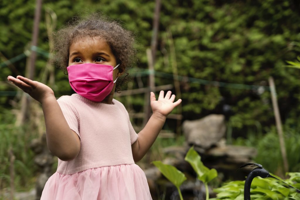 Smiling toddler in mask at pre-school