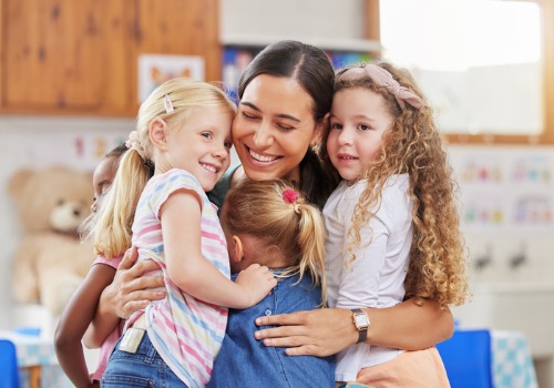 A teacher hugs her preschool students. Getting to know teachers and other students ahead of time is a good plan for preschool prep.