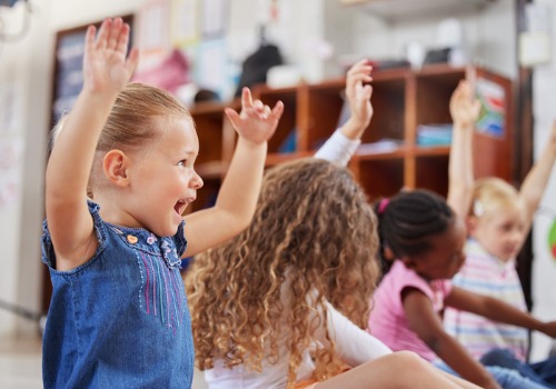 Children raise their hands at PALS, a top Childcare Development Center for Peoria Heights IL residents