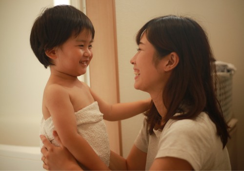 A mother wraps her child in a towel after bath time as a way to create a nighttime routine for a toddler