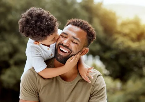 A boy hugs his dad, which is one of many examples of Random Acts of Kindness.