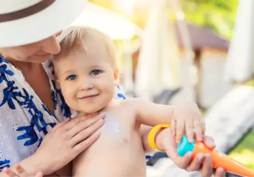A mother puts sunscreen on her child, which is one of the top Outdoor Safety Tips for Kids to learn.