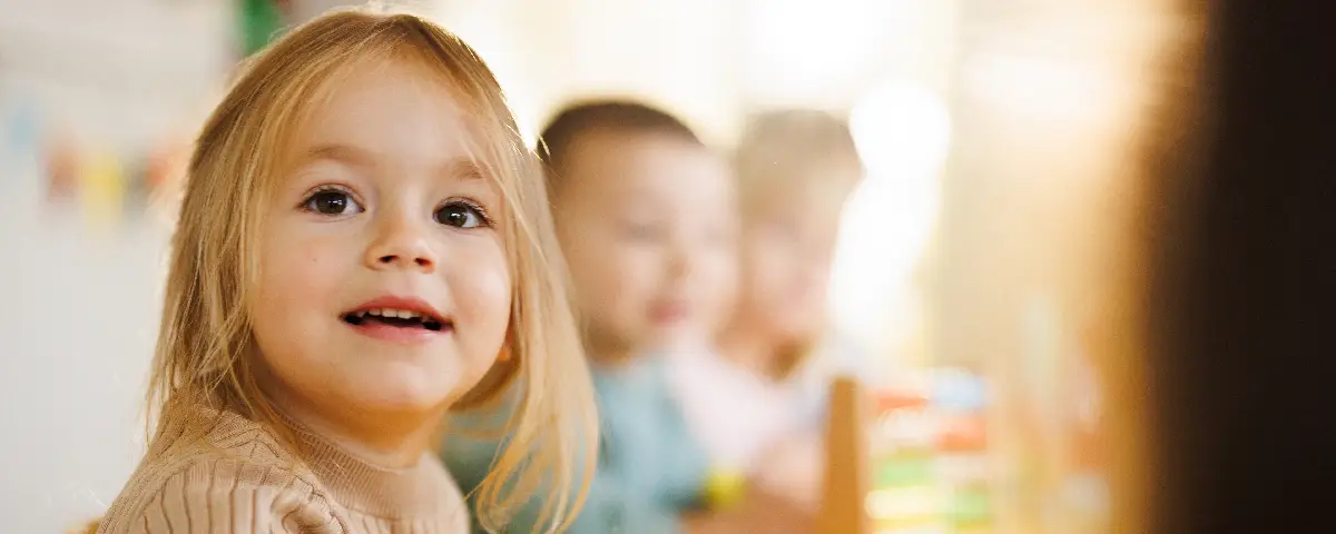 A cute little girl sitting at the table in kindergarten at PALS. Our Programs & Curriculum are perfect for infants through Pre-K.