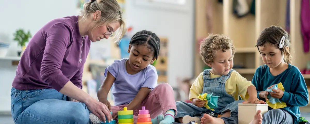 A teacher and preschoolers play with toys at PALS, a Peoria Area Childcare & Preschool