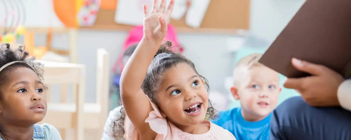 A girl from PALS’ Pre-K Program raises her hand to ask a question in her classroom.