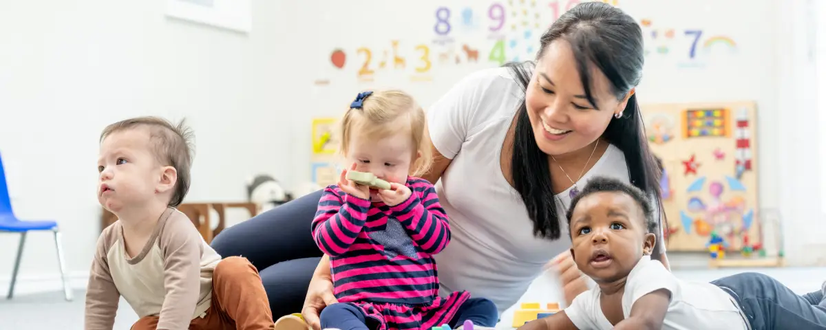 Three babies at PALS get playtime in the infant program while their teacher plays on the floor with them