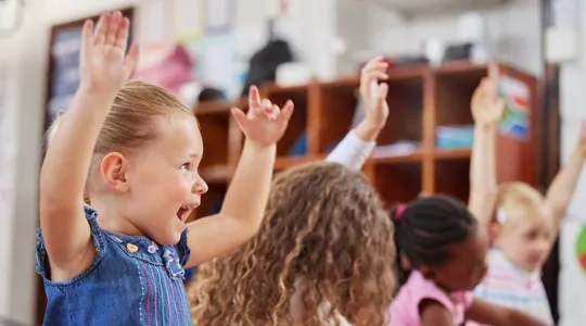 A group of children in the PALS toddler program throw their arms in the air during a music group session