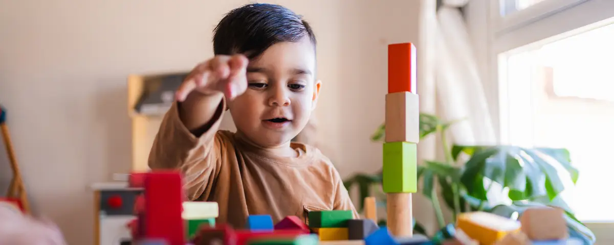 A young boy has fun playing with wooden blocks in PALS’ Two’s and Three’s Program
